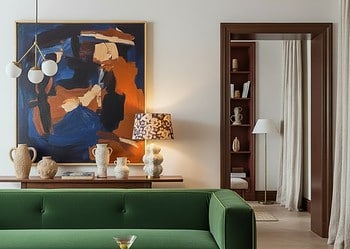 White living room with velvet rug, wall decor and velvet sofa adding depth to white walls.